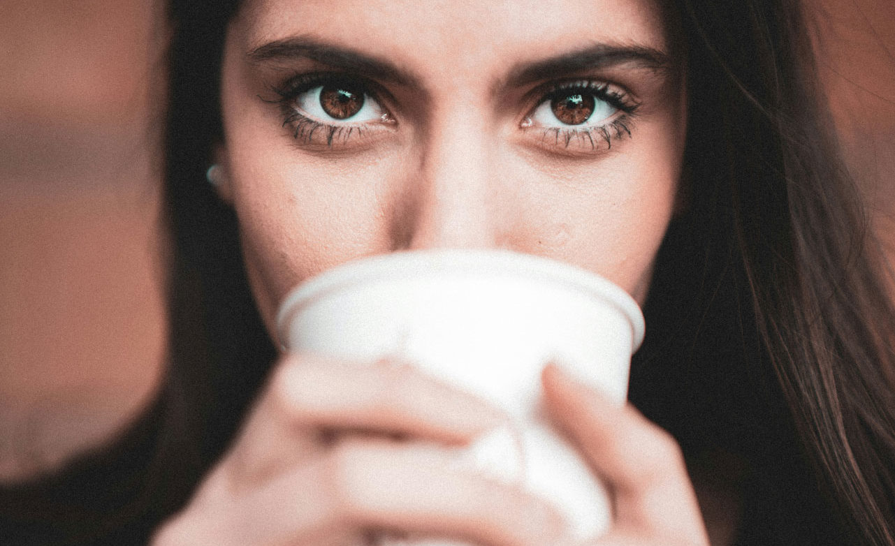 Une jeune femme buvant un café sans lunettes pour illustrer les Bénéfices d’une Opération Réfractive : Une Vision Transformée au Quotidien