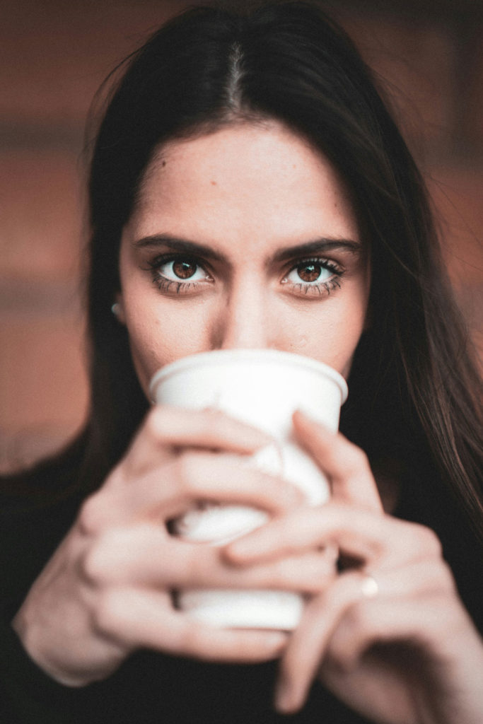 Une jeune femme buvant un café sans lunettes pour illustrer les Bénéfices d’une Opération Réfractive : Une Vision Transformée au Quotidien